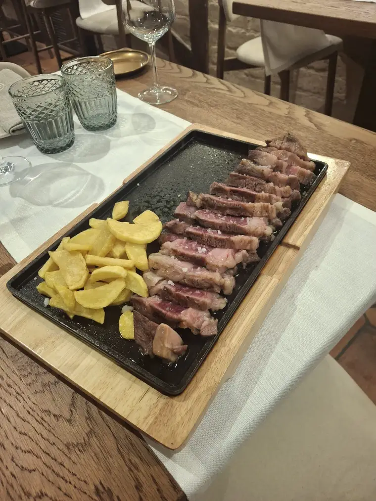 Entrecot a la brasa servido en plancha de hierro sobre tabla de madera